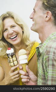 Close-up of a mature couple holding ice cream cones and smiling
