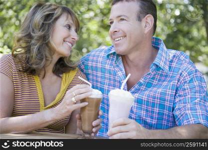 Close-up of a mature couple holding milk shakes and smiling