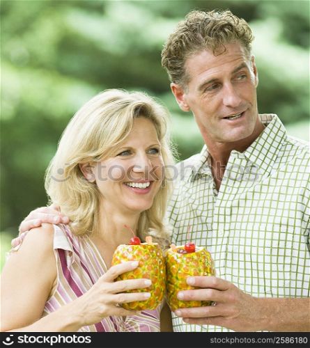Close-up of a mature couple holding pineapples and smiling