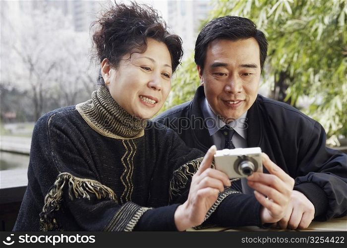 Close-up of a mature couple looking at a digital camera smiling