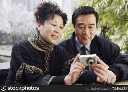 Close-up of a mature couple looking at a digital camera smiling