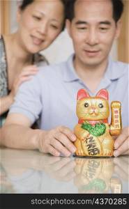 Close-up of a mature couple looking at a Maneki Neko figurine