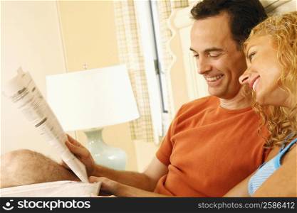 Close-up of a mature couple reclining on the bed and reading newspapers