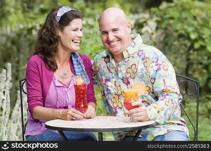 Close-up of a mature couple sitting at a table and holding glasses of juice