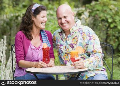 Close-up of a mature couple sitting at a table and holding glasses of juice