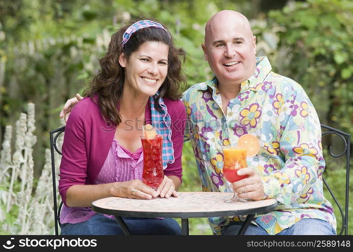 Close-up of a mature couple sitting at a table and holding glasses of juice