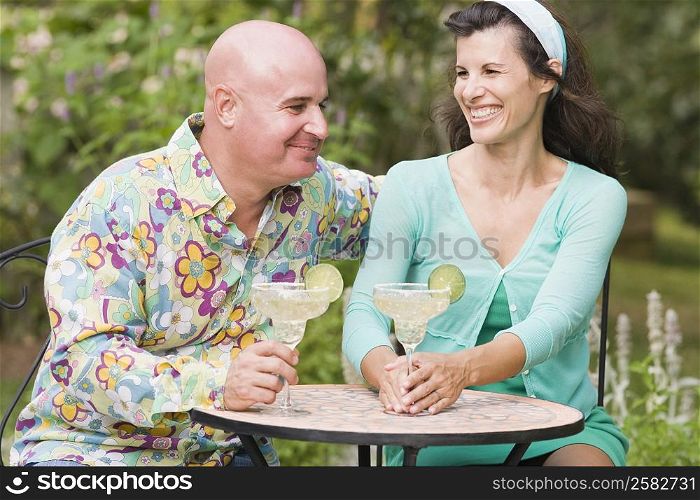 Close-up of a mature couple sitting at a table and holding martini glasses