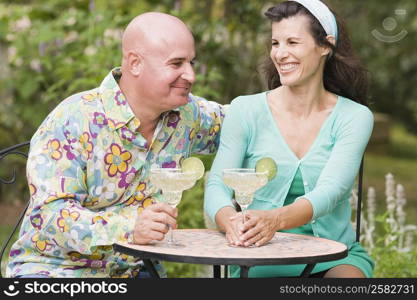 Close-up of a mature couple sitting at a table and holding martini glasses