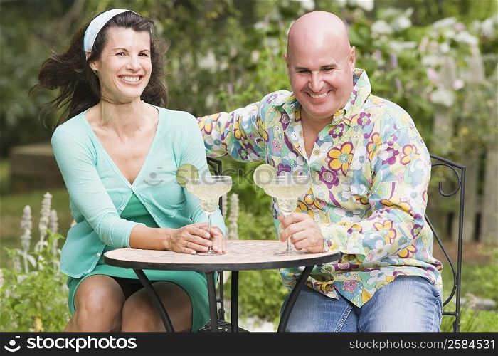 Close-up of a mature couple sitting at a table and holding martini glasses