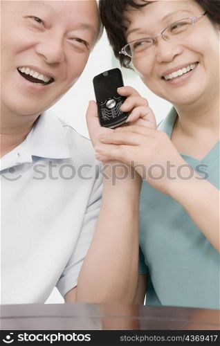 Close-up of a mature couple smiling and holding a mobile phone