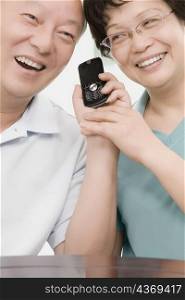 Close-up of a mature couple smiling and holding a mobile phone