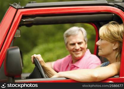 Close-up of a mature couple smiling in a sports utility vehicle