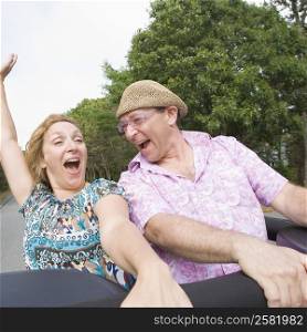 Close-up of a mature couple standing on a jeep and shouting