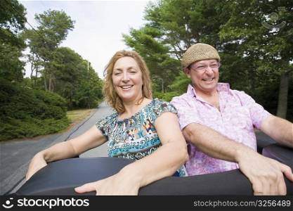 Close-up of a mature couple standing on a jeep and smiling
