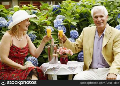 Close-up of a mature couple toasting glasses of juice