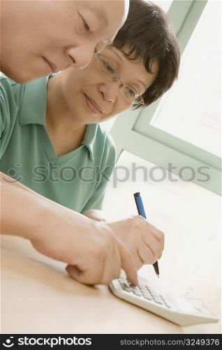 Close-up of a mature couple using a calculator