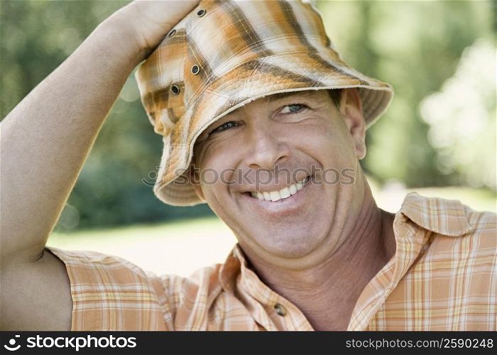 Close-up of a mature man adjusting his hat
