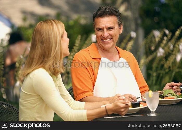 Close-up of a mature man and a mid adult woman sitting at the table and smiling