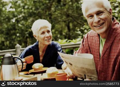 Close-up of a mature man and a senior woman sitting at the table and smiling