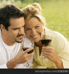 Close-up of a mature man and a young woman holding glasses of red wine