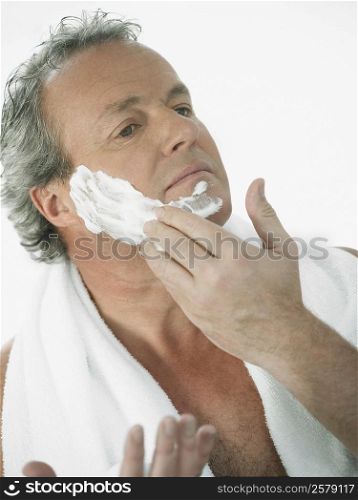 Close-up of a mature man applying shaving cream on his face