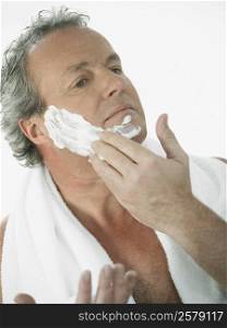 Close-up of a mature man applying shaving cream on his face