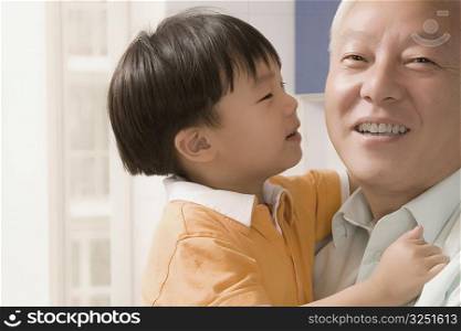 Close-up of a mature man carrying his grandson