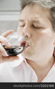 Close-up of a mature man drinking a glass of red wine