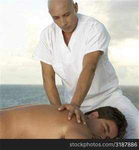 Close-up of a mature man giving a mid adult man a back massage