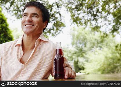 Close-up of a mature man holding a bottle of red wine and smiling