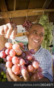 Close-up of a mature man holding a bunch of red grapes, Santo Domingo, Dominican Republic