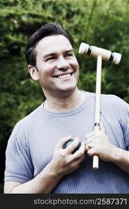 Close-up of a mature man holding a croquet mallet and a ball
