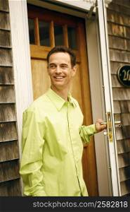 Close-up of a mature man holding a door handle and smiling