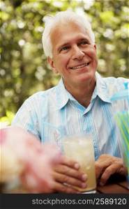 Close-up of a mature man holding a glass of a juice and smiling