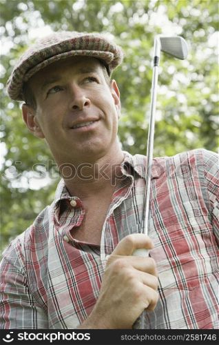 Close-up of a mature man holding a golf ball and a golf club