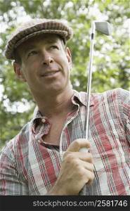 Close-up of a mature man holding a golf ball and a golf club