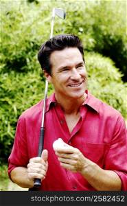 Close-up of a mature man holding a golf club and a golf ball