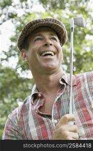 Close-up of a mature man holding a golf club and laughing