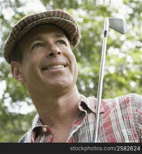 Close-up of a mature man holding a golf club and smiling
