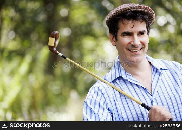Close-up of a mature man holding a golf club and smiling