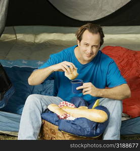 Close-up of a mature man holding a mug and a piece of bread