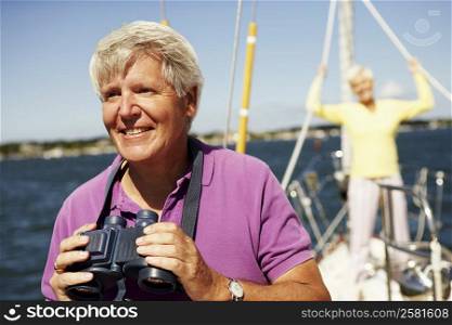Close-up of a mature man holding a pair of binoculars in a boat with a mature woman standing behind him