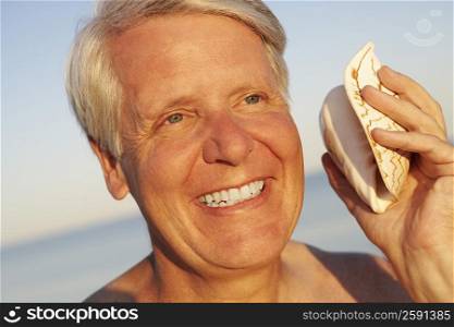 Close-up of a mature man holding a seashell and smiling