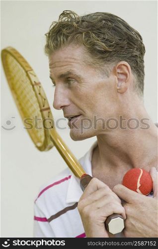 Close-up of a mature man holding a tennis racket and a tennis ball