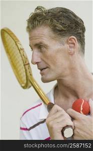 Close-up of a mature man holding a tennis racket and a tennis ball
