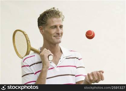 Close-up of a mature man holding a tennis racket and tossing a tennis ball