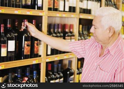 Close-up of a mature man holding a wine bottle in a liquor store