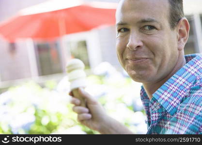 Close-up of a mature man holding an ice cream cone and smirking