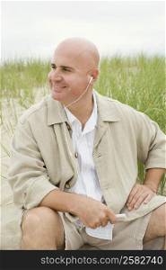 Close-up of a mature man listening to an MP3 player on the beach