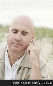 Close-up of a mature man listening to music with earbuds